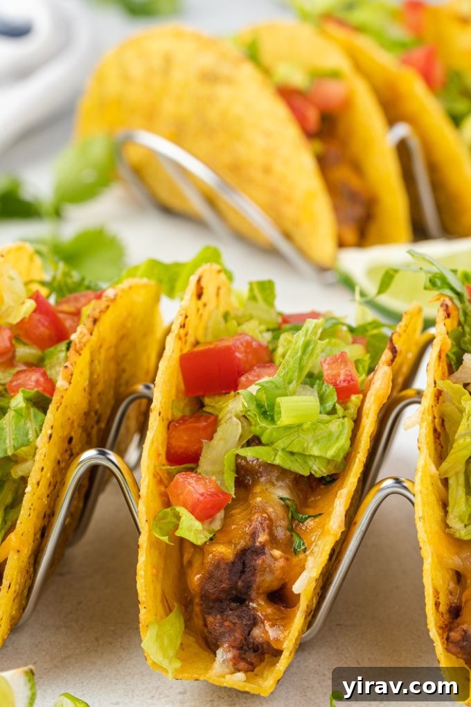 Golden Brown Turkey Tacos 3 Golden brown Oven Baked Turkey Tacos standing upright in a taco holder, garnished with fresh cilantro and lime.