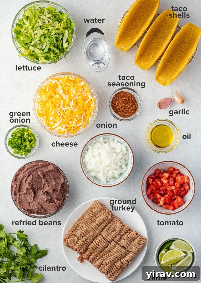 Golden Brown Turkey Tacos 4 Ingredients laid out for ground turkey tacos, including ground turkey, spices, onions, garlic, refried beans, taco shells, and cheese.