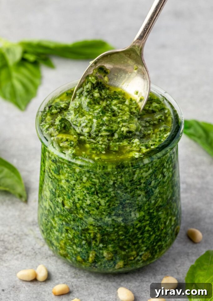 Fresh basil pesto in a glass jar with a spoon, ready to be served
