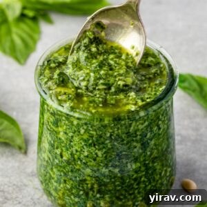 Fresh basil pesto in a glass jar with a spoon, ready to be served