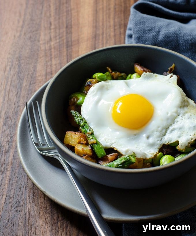 Hearty Breakfast Hash with an egg on top, featuring asparagus, fava beans, and potatoes.