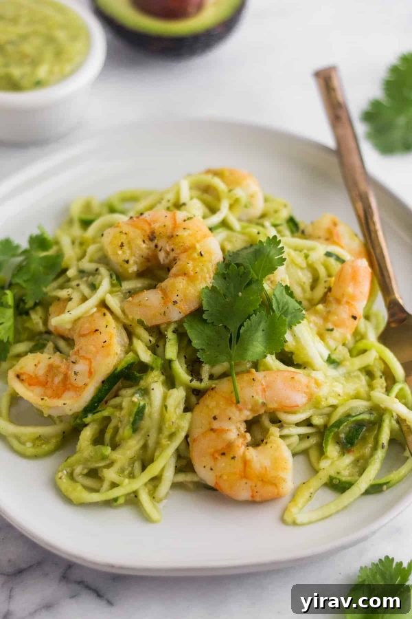 Tomatillo salsa shrimp zoodles on a white plate with a fork.