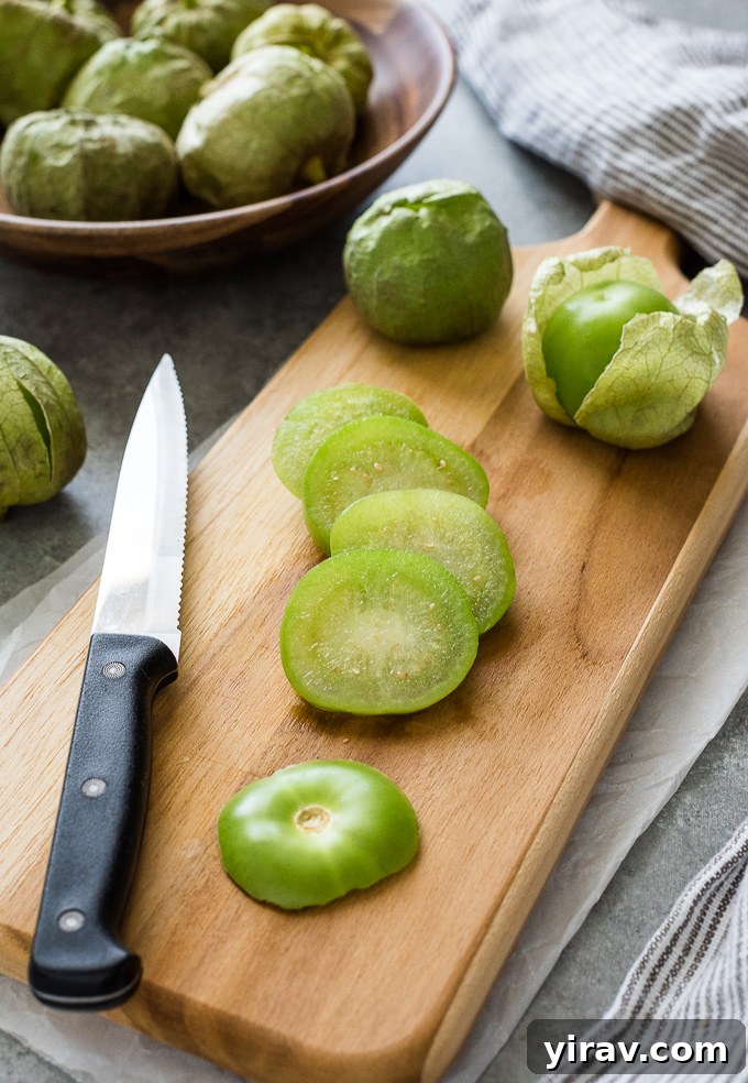 Sliced tomatillo on a cutting board with a knife