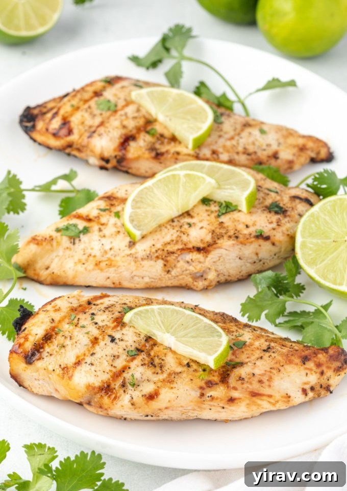 Grilled tequila lime chicken on a white platter garnished with lime slices and cilantro