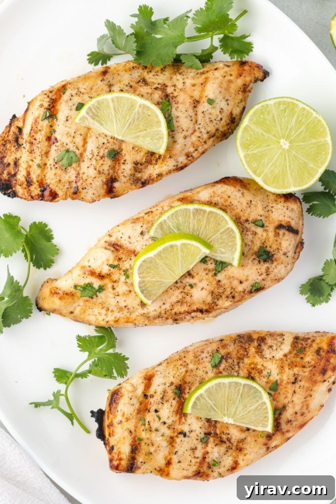 Grilled tequila lime chicken on a platter with lime slices and cilantro garnish