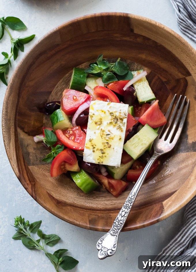 Horiatiki salad in a teak bowl with a whole block of feta on top