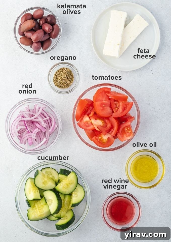 Fresh ingredients for Greek horiatiki salad including tomatoes, cucumber, red onion, olives, and a block of feta