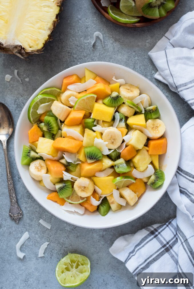 Fruit salad with tropical fruit in a white bowl, ready to serve.