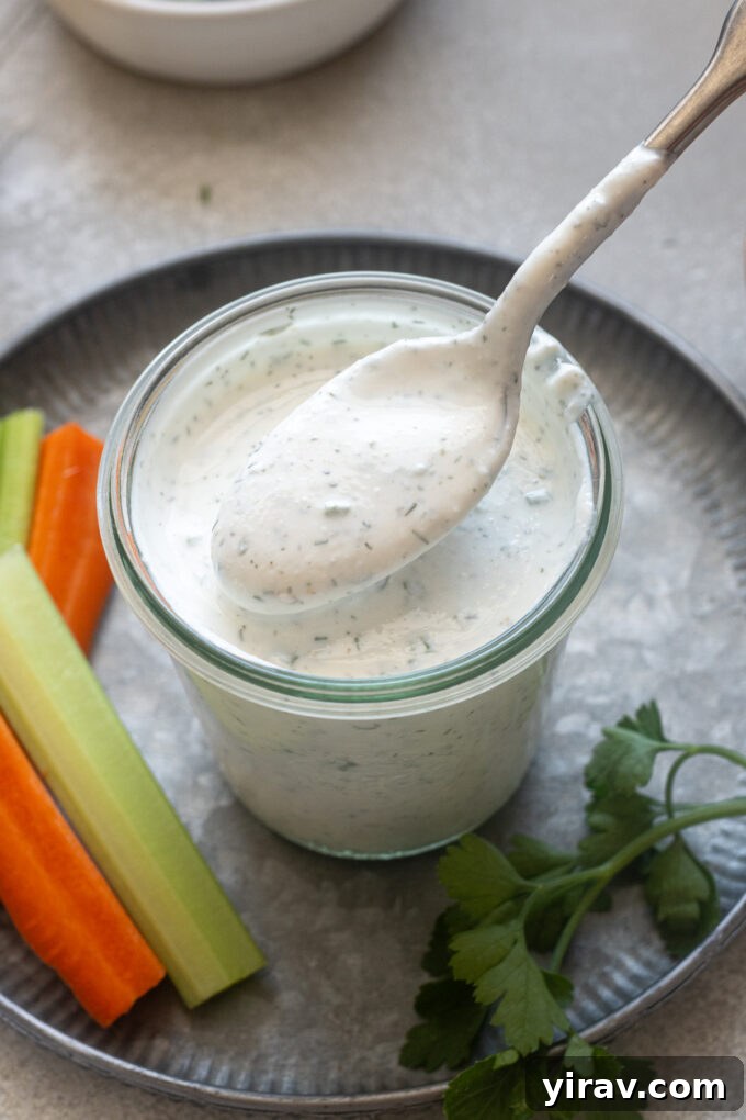 Spoonful of Greek yogurt ranch dressing over a jar.