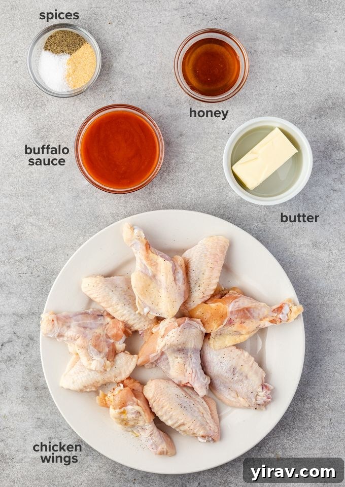 A flat lay photograph showcasing all the fresh ingredients needed for Instant Pot chicken wings, including chicken wings, butter, buffalo sauce, honey, and garlic powder.