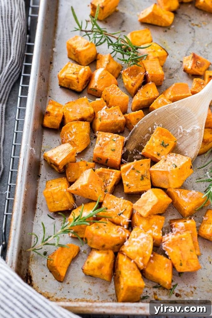 Sweet potato cubes tossed with olive oil and spices on a baking sheet, ready for roasting.