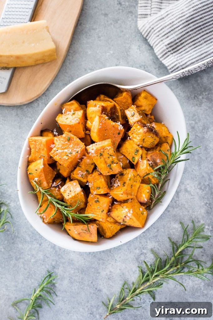 A white serving bowl filled with golden, oven-roasted sweet potatoes.
