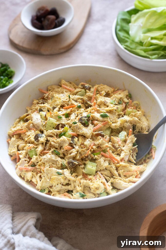 Creamy curry chicken salad with a serving spoon digging in, showcasing the rich, vibrant texture and colorful ingredients.