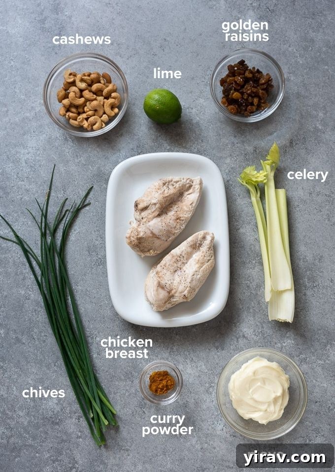 All the fresh ingredients laid out for making curry chicken salad, including cooked chicken, assorted fresh vegetables, dried apricots, and sliced almonds.