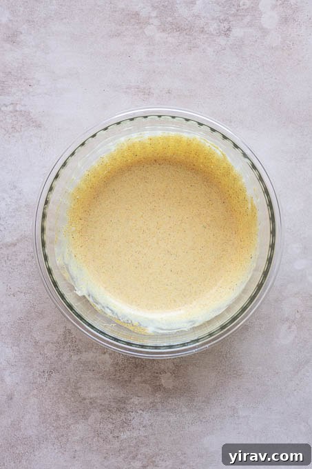 Creamy curry dressing being whisked in a small bowl until smooth.