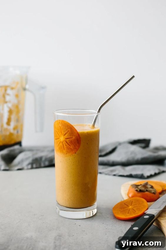 A refreshing persimmon smoothie served in a glass with a straw, garnished with fresh fruit.