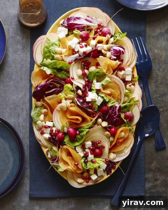 An overhead view of a colorful fall harvest salad presented on a large serving platter.