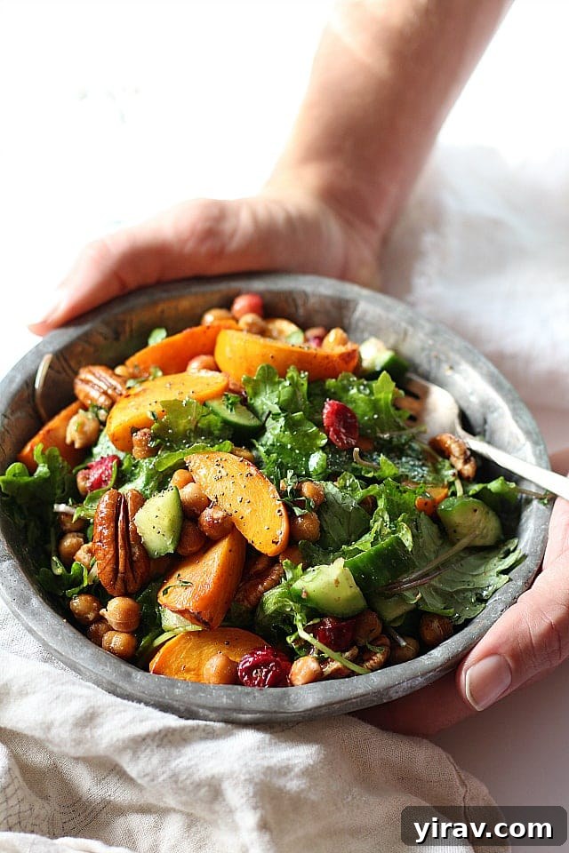A vibrant kale salad featuring chickpeas, cranberries, and persimmon in a rustic bowl.