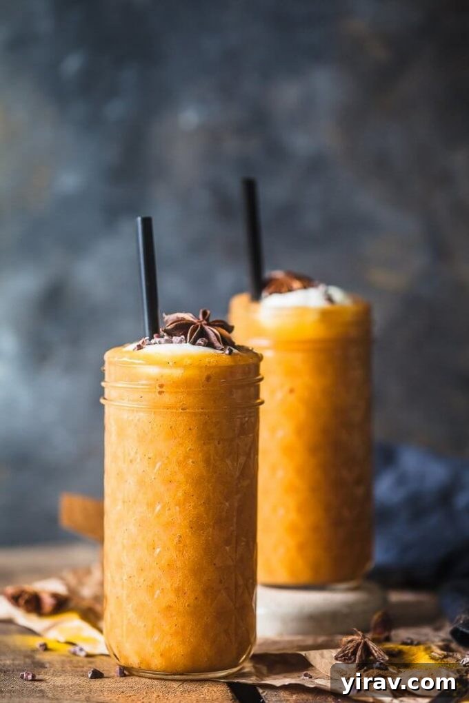 Two vibrant turmeric persimmon smoothies in glasses with straws, showcasing their golden hue.