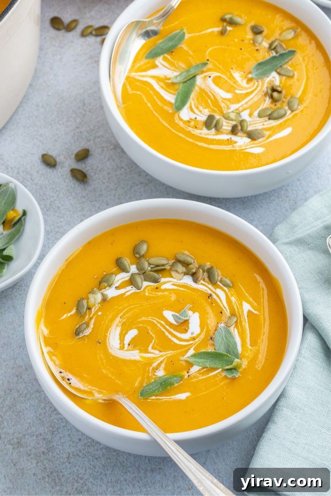 Bowls of Roasted Pumpkin Apple Soup with a spoon digging in, showcasing its creamy texture.