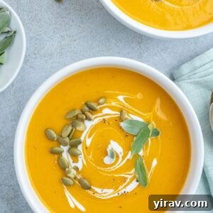Roasted pumpkin soup in bowls with coconut milk and sage garnish