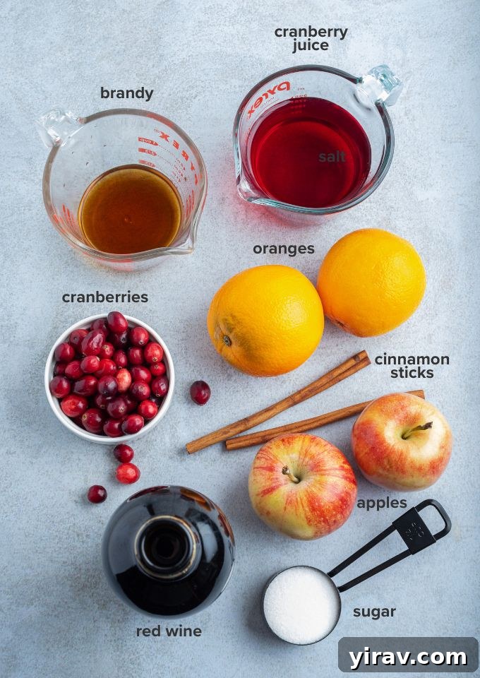 Various ingredients for cranberry sangria including fruit, wine, and cinnamon sticks