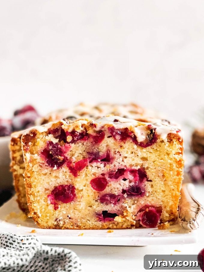 A beautifully sliced loaf of cranberry orange bread, showcasing its vibrant interior.