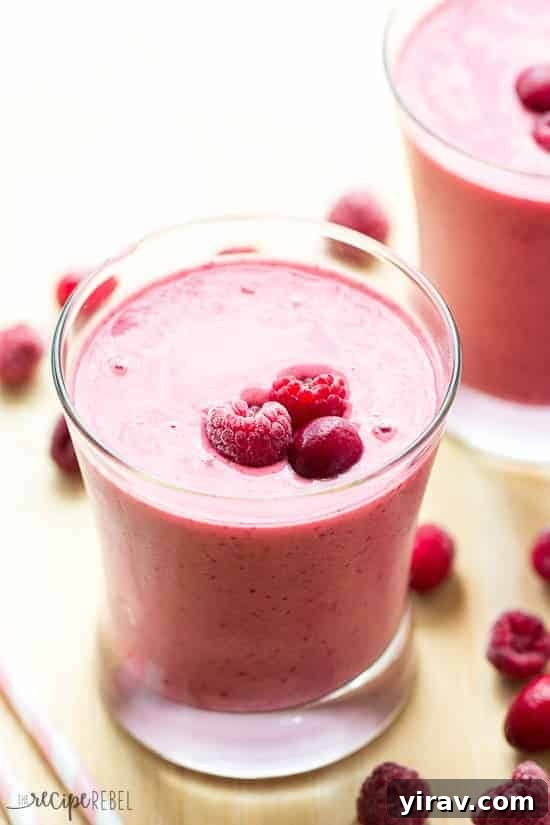 A refreshing glass of cranberry raspberry smoothie, garnished with fresh berries.