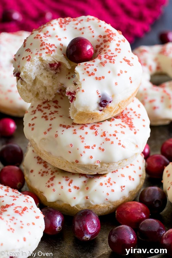 A stack of three perfectly glazed cranberry donuts, tempting and delicious.