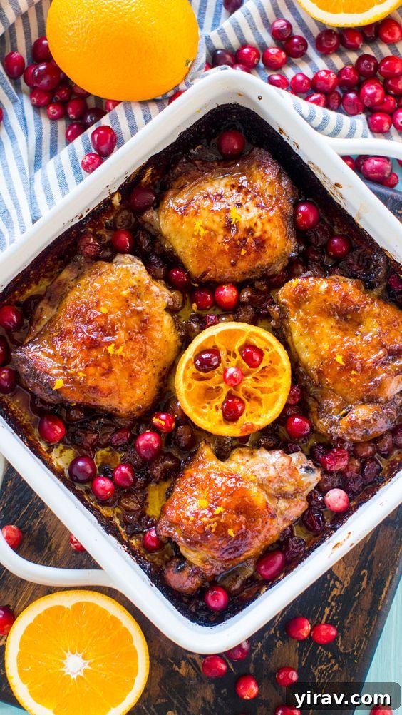 An overhead view of cranberry orange chicken baked in a white baking dish.