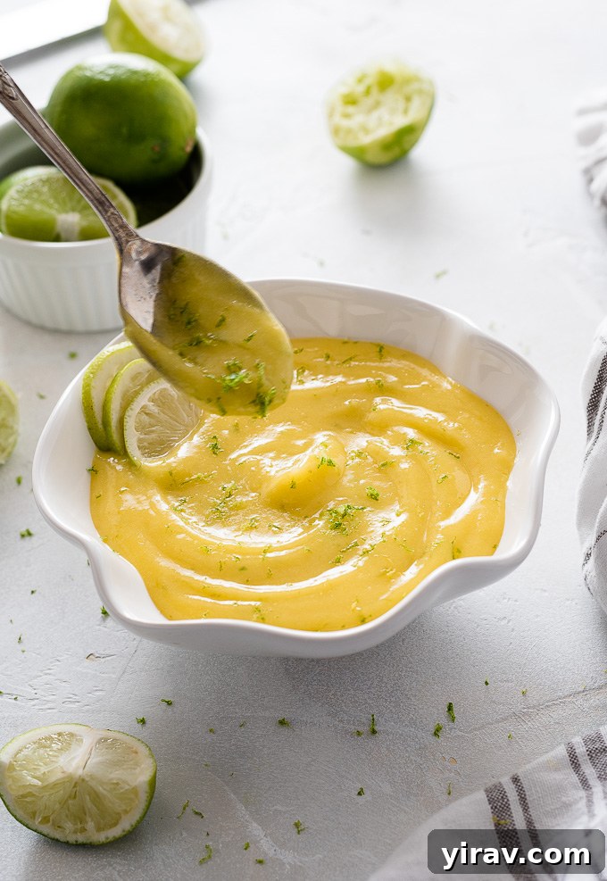 A spoon resting over a bowl of vibrant homemade lime curd, ready to be enjoyed.