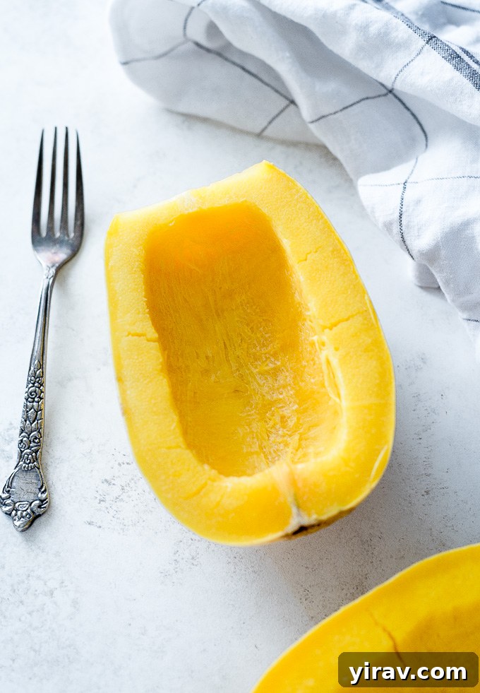 A whole spaghetti squash and two halves on a wooden board