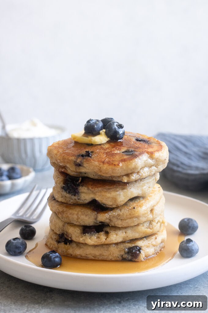 Fluffy Greek yogurt pancakes with blueberries on a plate.