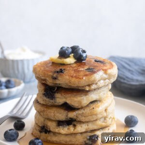 Fluffy Greek yogurt pancakes with blueberries on a plate.