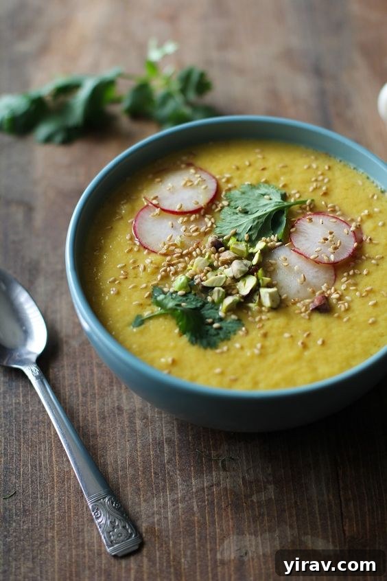 A vibrant bowl of Golden Beet and Fennel Soup, served next to a spoon.