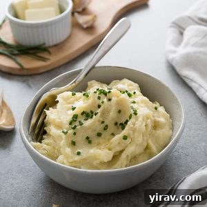 Bowl of creamy garlic mashed potatoes topped with fresh chives, ready to serve.