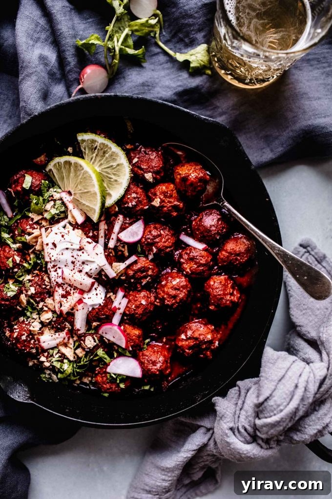Mexican meatballs in a cast iron skillet, garnished with fresh toppings.