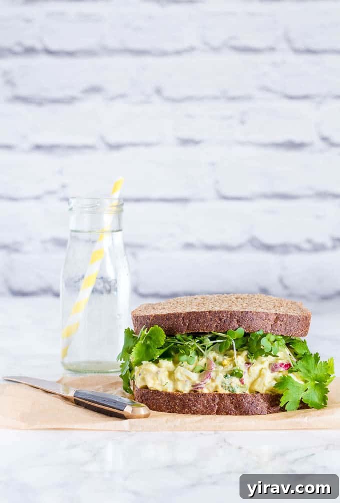 An egg salad sandwich next to a jug of water, a refreshing lunch.