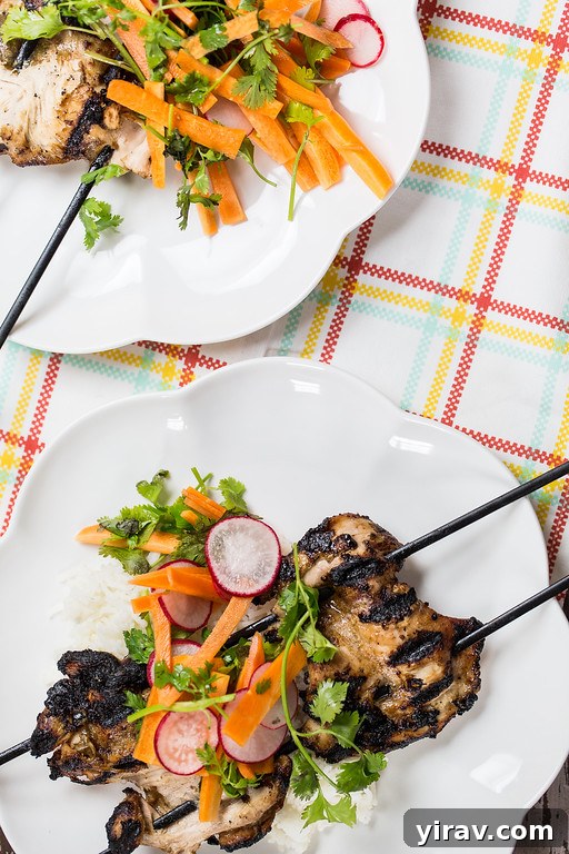 Five spice chicken skewers on a white plate, served with a fresh slaw.