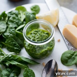 Pesto sauce in jar with greens, lemon and parmesan, showcasing the final product.
