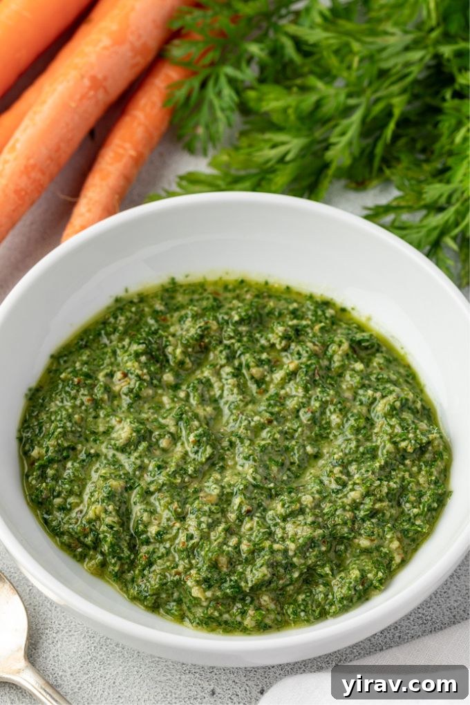 Vibrant Carrot Greens Pesto 6 A bowl of fresh carrot top pesto with whole carrots on the side, ready to be served.