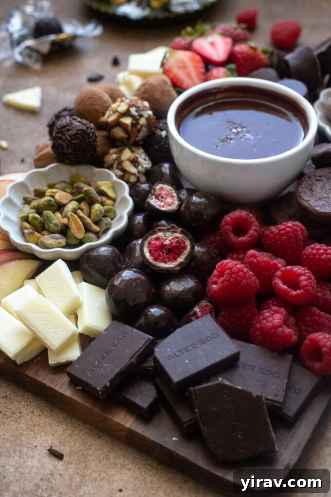 A stunning chocolate charcuterie board featuring a mix of rich chocolate ganache, various chocolate squares, fresh fruit, and crunchy nuts, artfully arranged for a dessert platter.