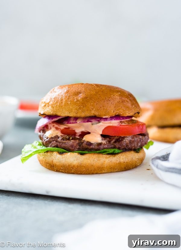 Grilling Burgers Like a Pro 2 A perfectly grilled classic burger on a pristine white plate, garnished with fresh lettuce and tomato.
