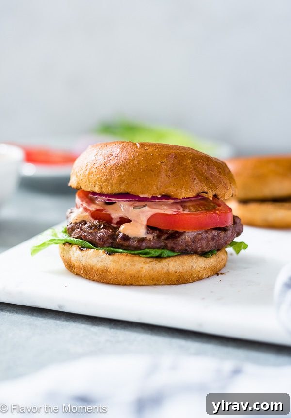 Grilling Burgers Like a Pro 4 A perfectly grilled burger patty, showcasing a beautiful sear and juicy interior, resting on a white plate.