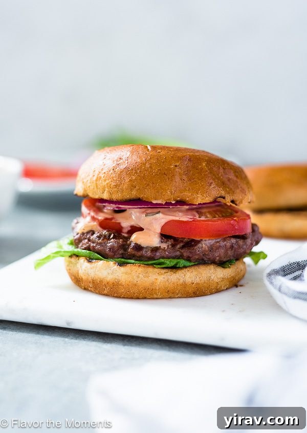 Grilling Burgers Like a Pro 6 A beautifully assembled grilled burger, ready to be enjoyed, presented on a white plate.