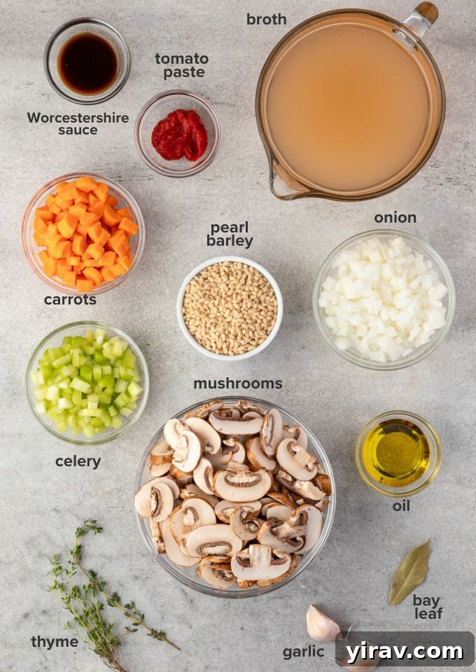 Various fresh ingredients laid out for mushroom barley soup: mushrooms, carrots, celery, onion, garlic, barley, and herbs