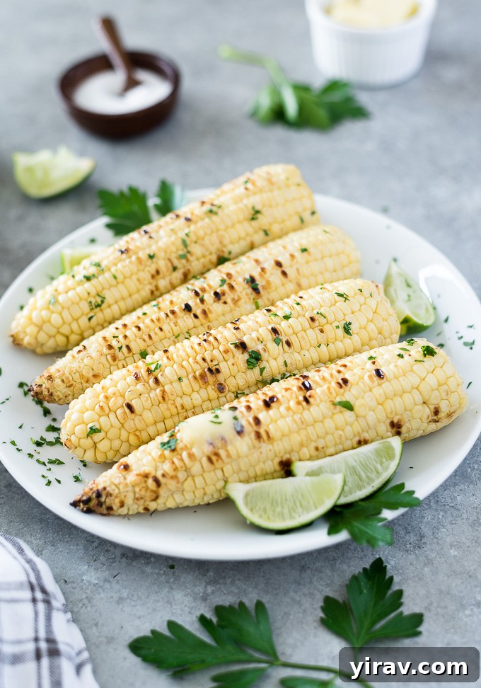 Ears of grilled corn on a white plate with lime
