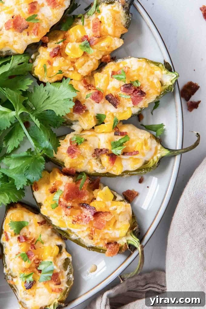 Golden-brown Corn Dip Stuffed Jalapeños, topped with crispy bacon bits, arranged on a serving platter.