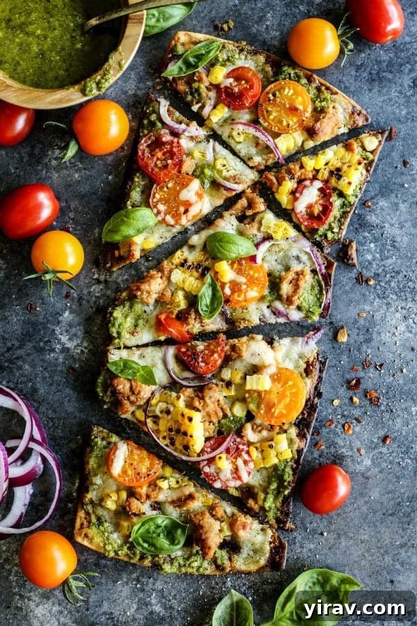 Overhead view of a freshly sliced Farmers Market Grilled Flatbread Pizza, topped with colorful seasonal vegetables.