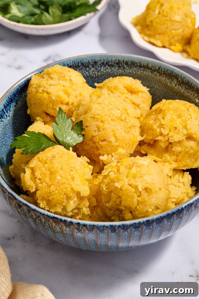 Scoops of golden Mexican Sweet Corn Cake in a bowl, garnished with a fresh cilantro sprig.